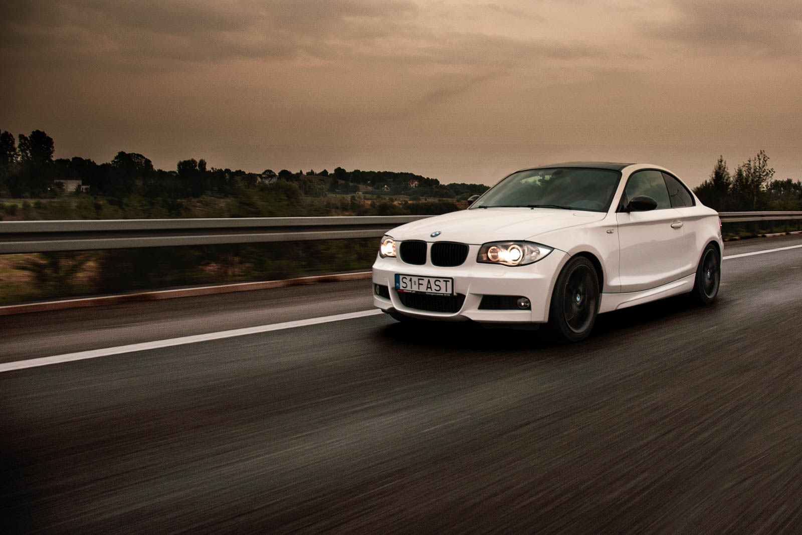 białe BMW jadące na autostradzie